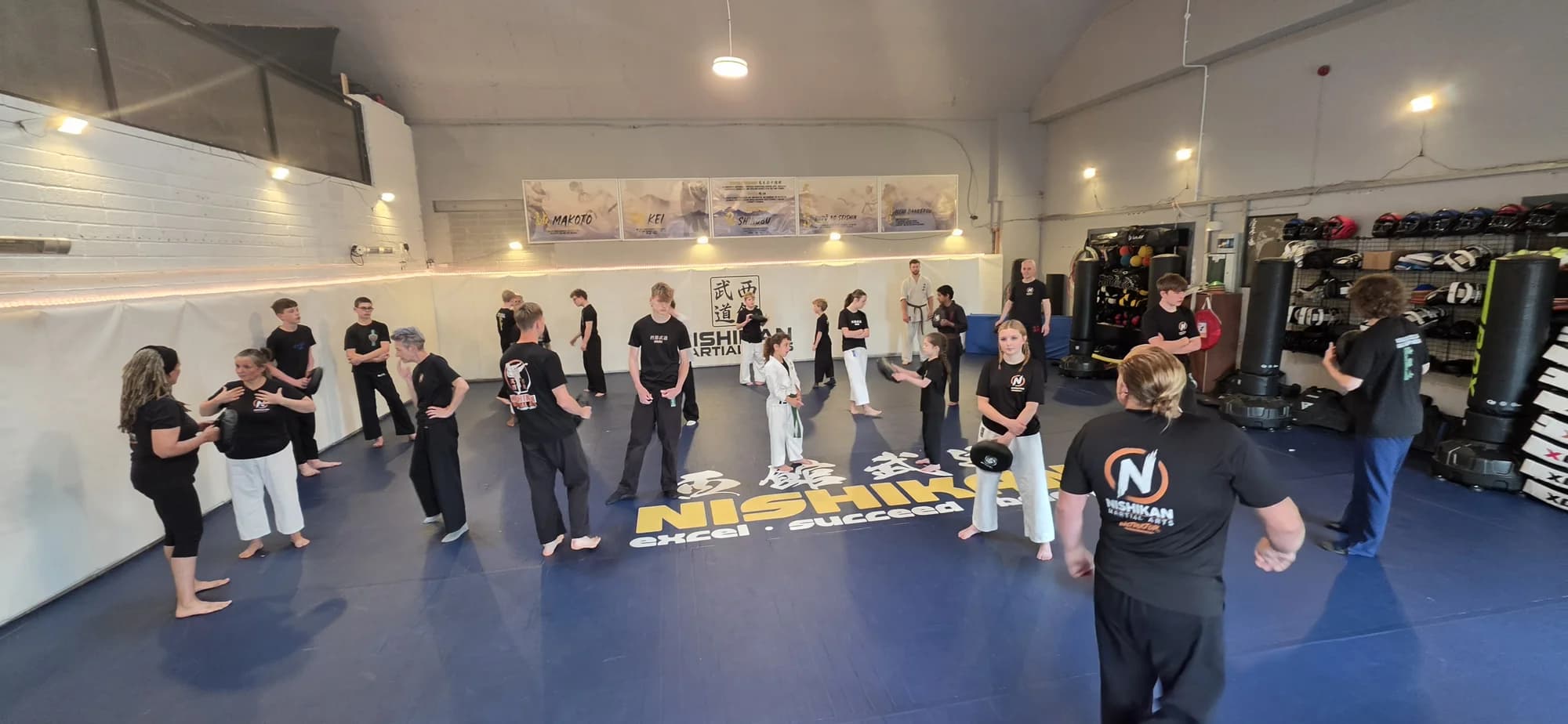 Students training together at Nishikan Martial Arts, working through pad drills on the mats